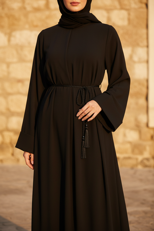 Full length — black abaya, outdoor stone wall, golden light